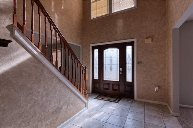 foyer featuring a towering ceiling and light tile floors