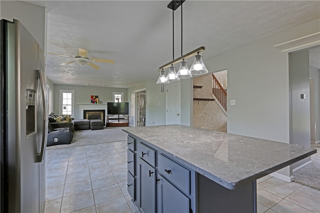 kitchen with ceiling fan, a center island, light tile floors, stainless steel fridge with ice dispenser, and pendant lighting