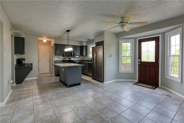 kitchen with ceiling fan, a center island, light tile floors, stainless steel appliances, and pendant lighting