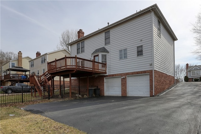 back of property featuring a wooden deck and a garage