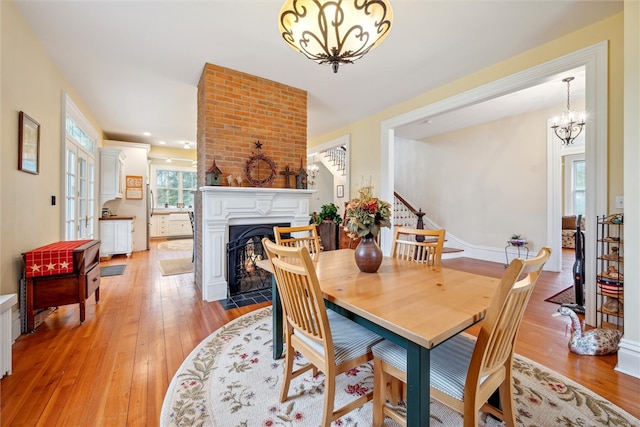 dining space featuring light hardwood / wood-style flooring, an inviting chandelier, and brick wall