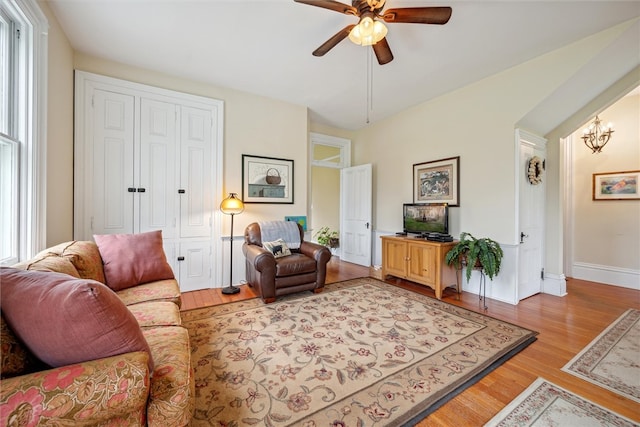 living room featuring a wealth of natural light, hardwood / wood-style flooring, and ceiling fan with notable chandelier