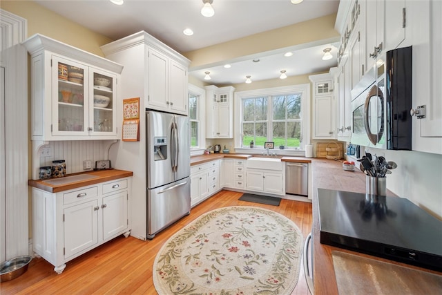 kitchen featuring stainless steel appliances, sink, white cabinetry, and light hardwood / wood-style floors