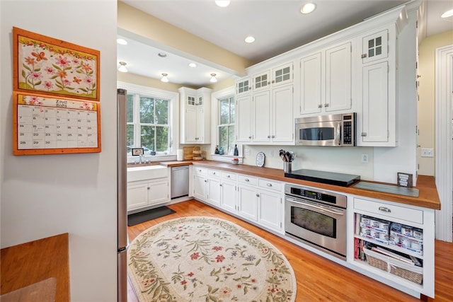 kitchen with stainless steel appliances, white cabinets, sink, and light wood-type flooring