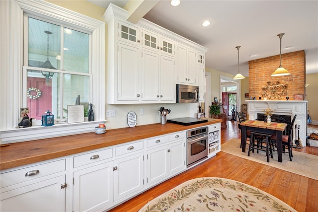 kitchen with stainless steel appliances, white cabinets, light wood-type flooring, and pendant lighting