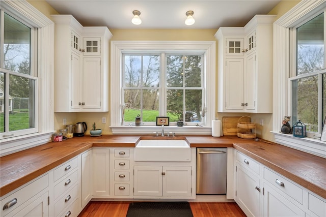 kitchen featuring white cabinetry, sink, butcher block counters, and stainless steel dishwasher