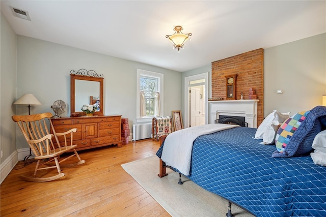 bedroom with hardwood / wood-style flooring, brick wall, and radiator