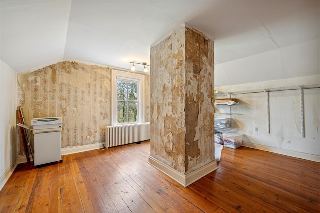 additional living space featuring lofted ceiling, hardwood / wood-style flooring, and radiator