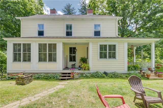 back of property with covered porch and a yard