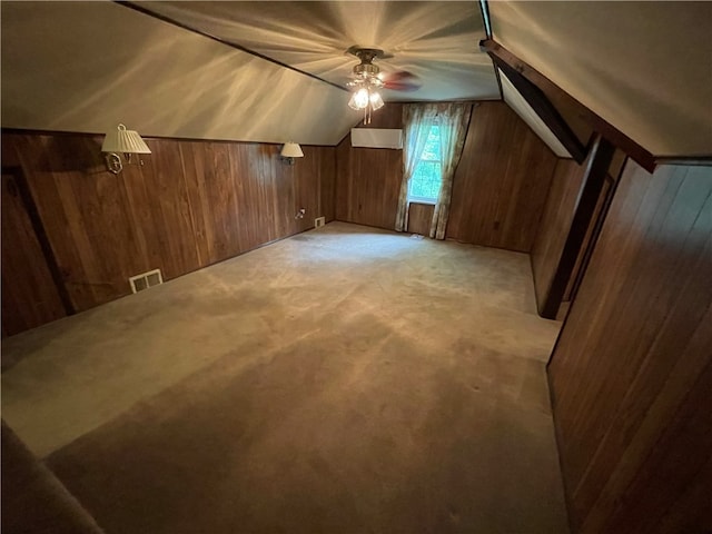 bonus room featuring ceiling fan, light colored carpet, wood walls, and lofted ceiling