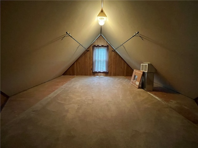 bonus room with vaulted ceiling, wooden walls, and carpet