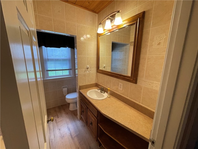 bathroom featuring hardwood / wood-style floors, wooden ceiling, toilet, vanity, and tile walls