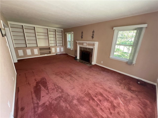 unfurnished living room featuring a high end fireplace and dark carpet