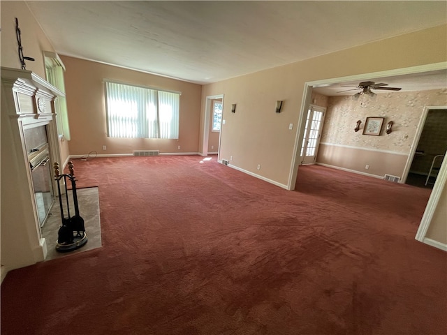 unfurnished living room with ceiling fan and carpet