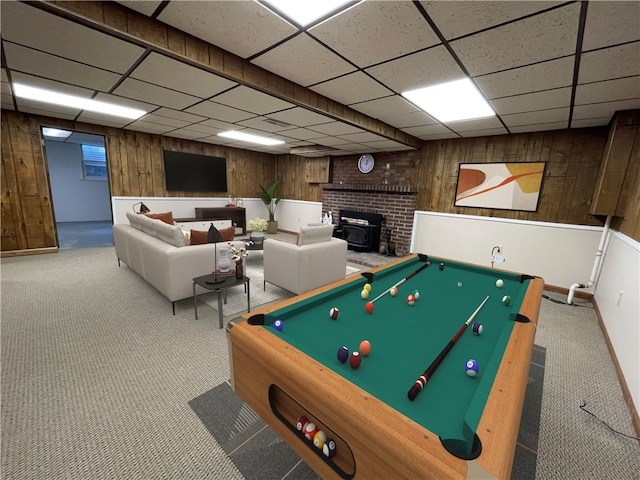 rec room with pool table, a paneled ceiling, carpet floors, wooden walls, and a wood stove