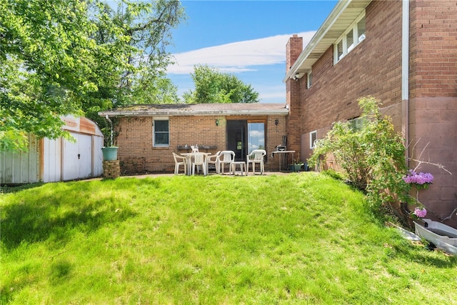 back of property featuring a patio area, a yard, and a storage shed