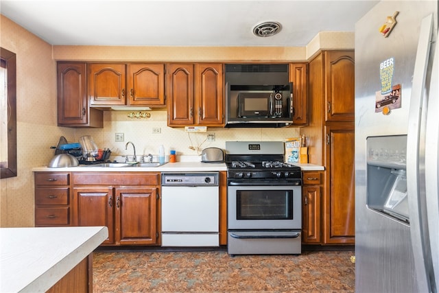 kitchen with sink, appliances with stainless steel finishes, backsplash, and dark tile flooring