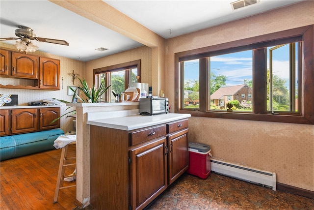 kitchen with ceiling fan, a baseboard radiator, a kitchen breakfast bar, and dark hardwood / wood-style floors