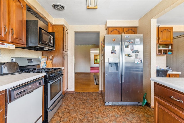 kitchen with dark tile floors, gas range oven, dishwasher, and stainless steel fridge