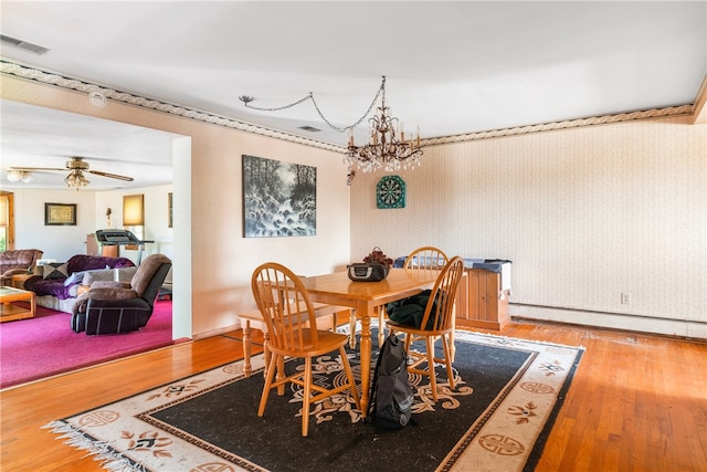 dining space with ceiling fan with notable chandelier, baseboard heating, and hardwood / wood-style floors