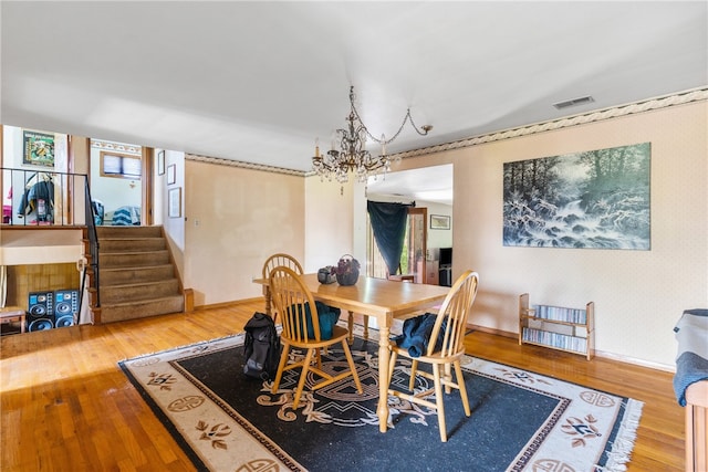 dining space with hardwood / wood-style floors and an inviting chandelier