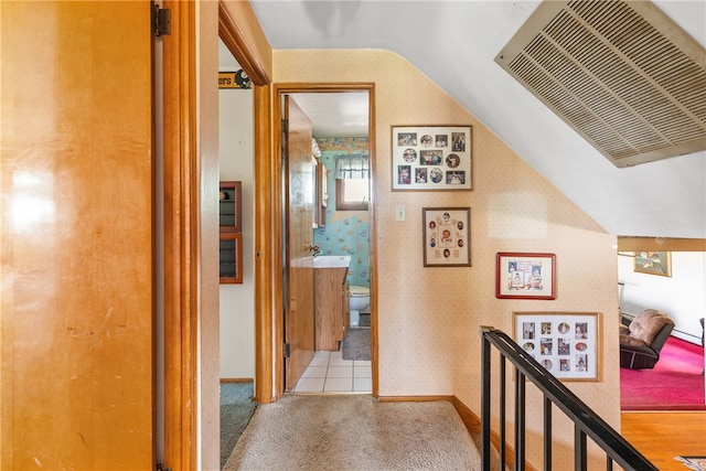 hall featuring wood-type flooring, sink, and vaulted ceiling