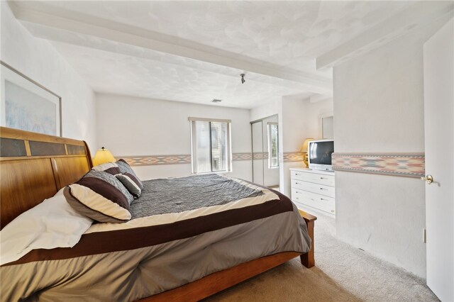 carpeted bedroom with beam ceiling