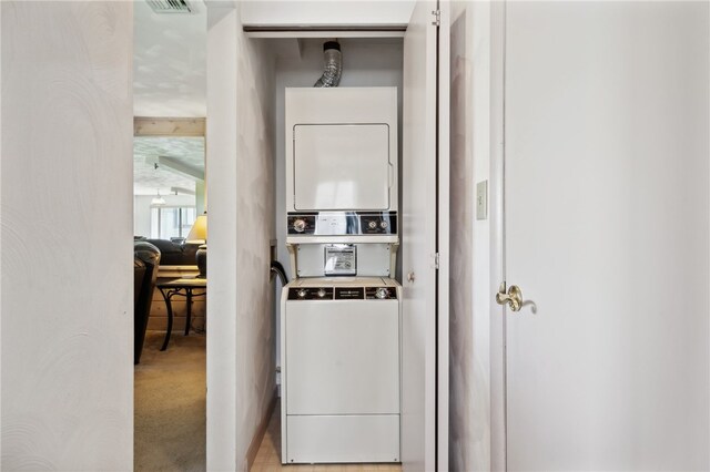 clothes washing area featuring light colored carpet and stacked washer / dryer