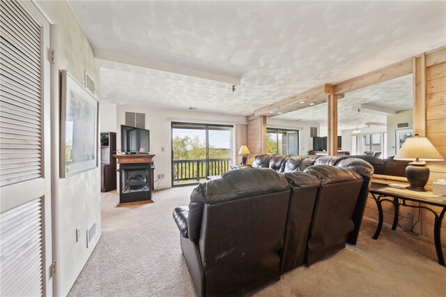 living room featuring light colored carpet, decorative columns, a textured ceiling, and a fireplace