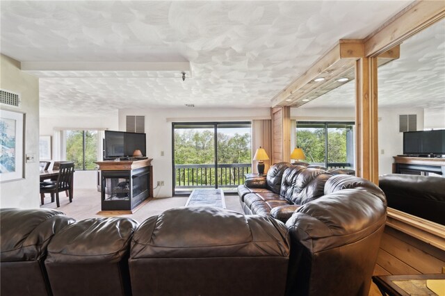 living room featuring a wealth of natural light, light colored carpet, and a textured ceiling