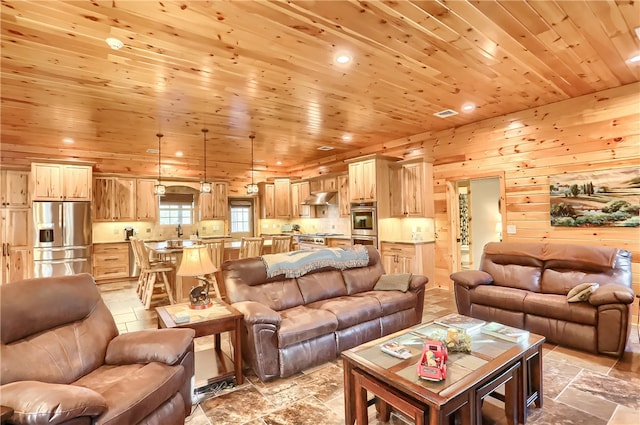 living room featuring wooden ceiling, wood walls, light tile floors, and sink