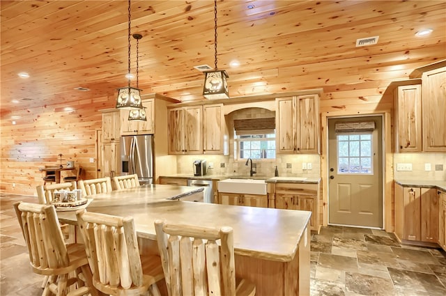 kitchen featuring tile flooring, a kitchen island, sink, hanging light fixtures, and stainless steel appliances