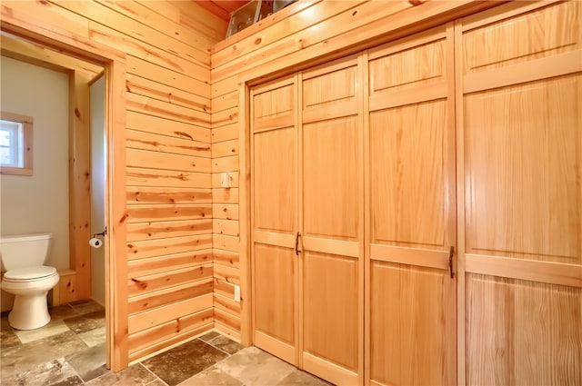 bathroom with wood walls, toilet, and tile flooring