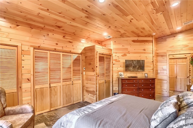 bedroom featuring lofted ceiling, wooden walls, wooden ceiling, two closets, and tile floors