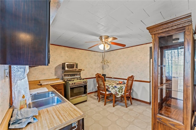 kitchen featuring ornamental molding, range with gas cooktop, sink, ceiling fan, and light tile floors