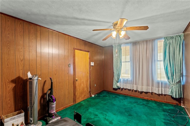 interior space featuring a textured ceiling, ceiling fan, and wood walls