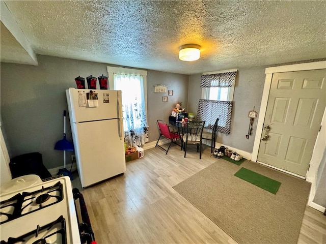 interior space featuring hardwood / wood-style floors, gas range oven, a textured ceiling, and white fridge