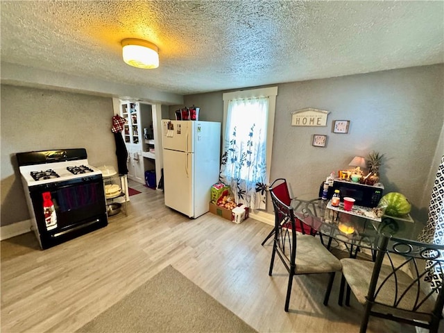 interior space with white refrigerator, gas stove, a textured ceiling, and light hardwood / wood-style flooring