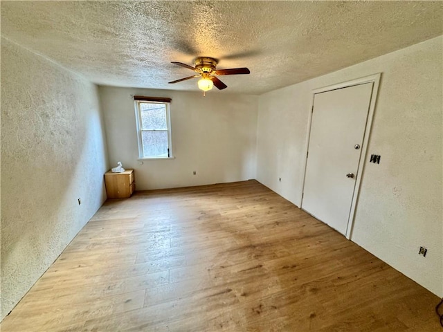 empty room featuring ceiling fan, a textured ceiling, and light hardwood / wood-style floors