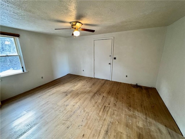 spare room with a textured ceiling, light hardwood / wood-style floors, and ceiling fan