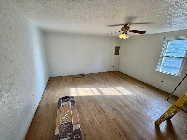 spare room featuring ceiling fan, hardwood / wood-style flooring, electric panel, and a textured ceiling