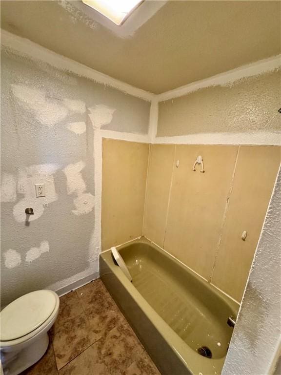 bathroom with tile patterned flooring, a washtub, and toilet