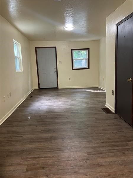 empty room featuring plenty of natural light and dark hardwood / wood-style floors