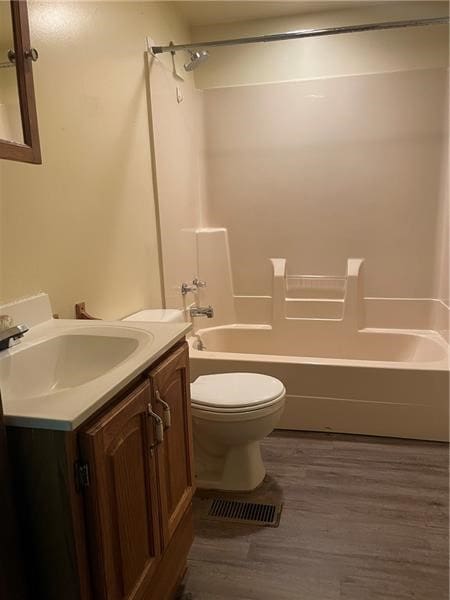 full bathroom with wood-type flooring, washtub / shower combination, vanity, and toilet