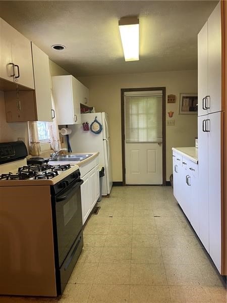 kitchen featuring sink, white cabinetry, light tile floors, and gas range gas stove