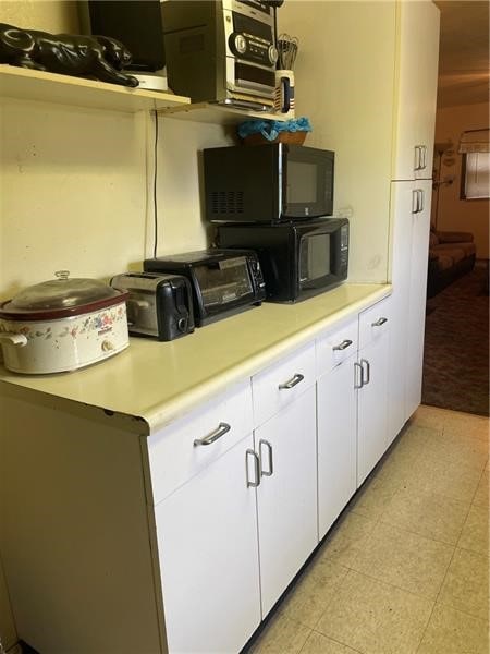 kitchen with light tile floors and white cabinetry