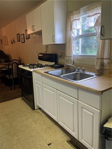 kitchen featuring sink, white cabinetry, light tile floors, and gas range gas stove