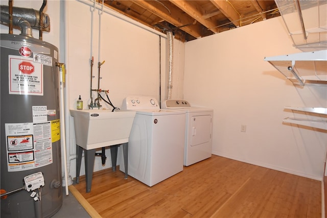 laundry room featuring water heater, light hardwood / wood-style flooring, and washer and clothes dryer