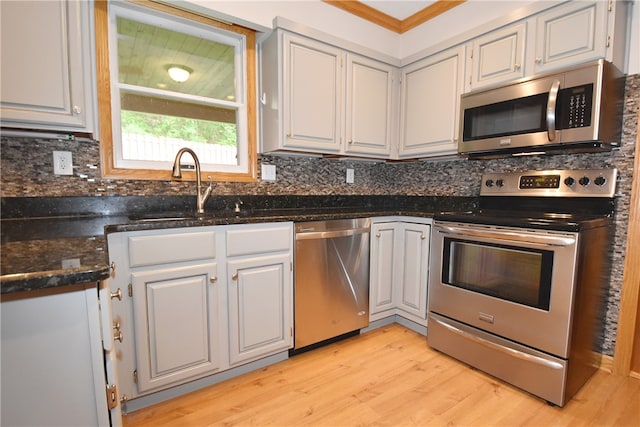 kitchen featuring white cabinets, backsplash, appliances with stainless steel finishes, sink, and light hardwood / wood-style floors