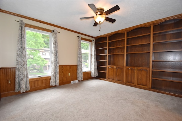 empty room with ornamental molding, carpet flooring, and ceiling fan